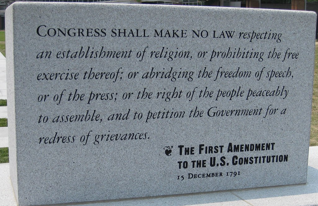 A photo of a granite monument carbed with, "Congress shall make no law respecting an establishment of religion, or prohibiting the free exercise thereof; of abridging the freedom of speech, or of the press; or the right of the people peaceably to assemble, and to petition the Government for a redress of grievances. The First Amendment to the US Constitution, 15 December 1791."